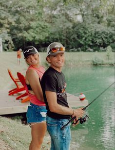 a man and woman standing next to each other holding fishing rods