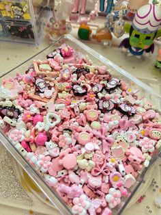 a plastic container filled with lots of pink and white candies on top of a table