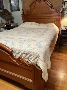 a bed sitting on top of a hard wood floor next to a wooden headboard