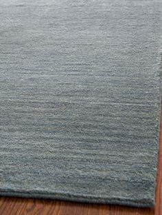 a blue rug on a wooden floor with a wood flooring area in the background