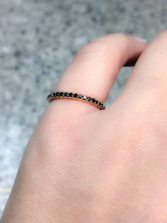 a woman's hand with a gold ring on top of her finger and a black diamond in the middle