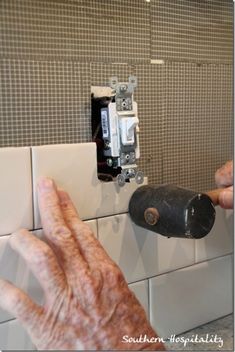 an old man is fixing a light switch on the wall with his hands and fingers