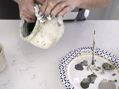 a person pouring something into a bowl on top of a white table with blue and yellow plates