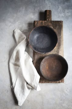 an old wooden tray with two bowls and a napkin on it next to a white cloth