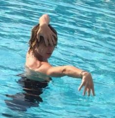 a man is swimming in the pool with his arm extended out to catch a frisbee