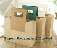 three brown paper bags sitting on top of a wooden table next to plates and cups