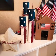 some patriotic candles are sitting on a white table with red, white and blue decorations