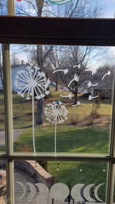 a window with some paper cut out of it's dandelions and birds