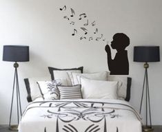 a bed room with a neatly made bed and a wall sticker that has musical notes coming out of it