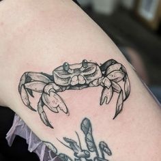 a black and white crab tattoo on the back of a woman's shoulder