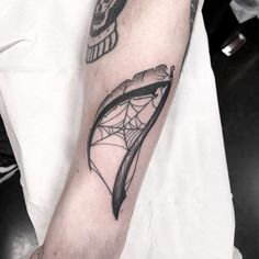 a black and white photo of a person's arm with a spider web tattoo on it