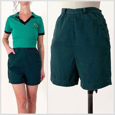 the woman is wearing green shorts and has her hands on her hips as she stands next to a mannequin