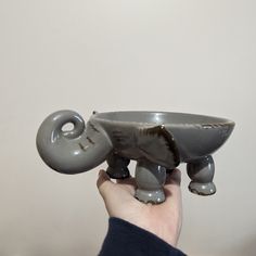 a person holding an elephant shaped bowl in their hand