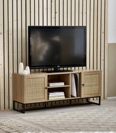 a flat screen tv sitting on top of a wooden entertainment center next to a wall