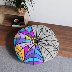 a colorful umbrella sits on the floor next to a potted plant