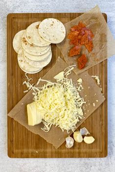 a cutting board topped with different types of cheeses and tortilla shells on top of each other