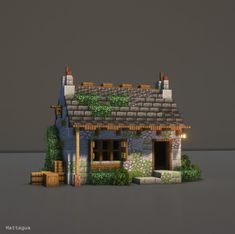 a small house made out of bricks and stone with grass growing on the roof, windows and door