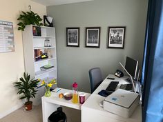 a desk with a laptop computer and printer on top of it next to a potted plant