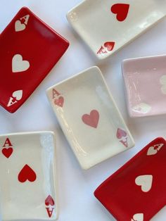 four red and white plates with hearts painted on the sides are arranged in a pattern