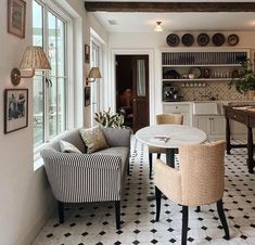 a dining room table and chairs in front of an open kitchen area with black and white checkered flooring