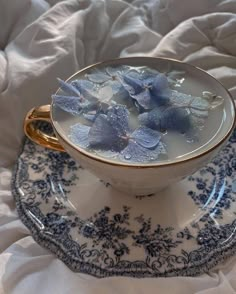 a blue and white cup with flowers in it on a saucer next to a plate