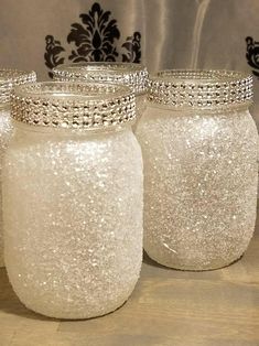 three glass jars are sitting on a table with silver trimmings and beading