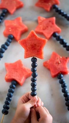 someone is making star shaped popsicles out of watermelon and black beads on a stick