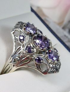 Purple CZ Ring Description 9Gem Design#69 Made To Order Inspired by the Art Deco movement, I now offer this gorgeous Art Deco 1930s reproduction filigree ring in sterling silver. This ring is marked 925 for solid sterling. This lovely filigree ring is set with 3 central stunning center round cut Purple/Amethyst CZ gemstones; 6mm center, 4mm top/bottom. 6 more round cut 2mm gemstones also grace the sides of the setting. Notice the beautiful design of the silver filigree setting and band. The ring Vintage Amethyst Ring With Intricate Design For Anniversary, Vintage Amethyst Ring With Accent Stones, Vintage Silver Amethyst Ring With Accent Stones, Vintage Filigree Ring With Accent Stones As Gift, Vintage Amethyst Ring With Accent Stones For Collectors, Antique Silver Amethyst Ring For Wedding, Vintage Silver Amethyst Ring With Center Stone, Antique Silver Amethyst Wedding Ring, Vintage Filigree Ring With Accent Stones For Gift