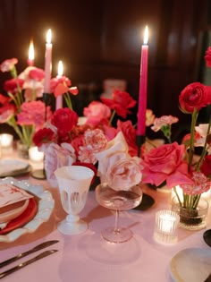 the table is set with pink flowers and candles for an elegant dinner or party setting