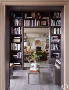 a living room filled with lots of furniture and bookshelves full of books on top of each shelf