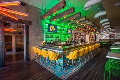 a bar with yellow chairs and neon lights