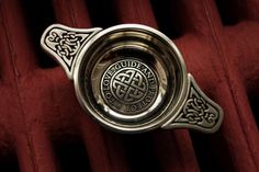 an ornate silver ring on top of a red velvet seat