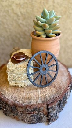 a small potted plant sitting on top of a tree stump next to a wagon wheel