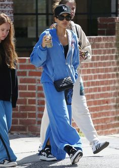 two women walking down the street with one holding a drink