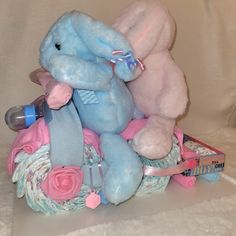 two stuffed animals sitting on top of each other in a basket with flowers and ribbons