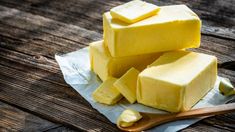 three blocks of butter sitting on top of a piece of wax paper next to a wooden spoon