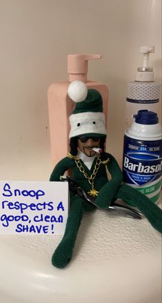 a stuffed animal sitting on top of a sink next to a bottle of shampoo