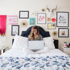 a woman is sitting on her bed with a laptop in front of her, surrounded by pictures and photos