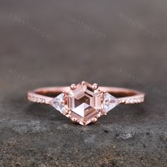 an engagement ring with a pink diamond in the center and two white diamonds on each side