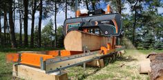 a machine that is cutting wood in the woods with it's back end extended