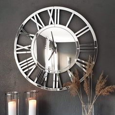 a clock that is on the wall next to some vases with flowers in it