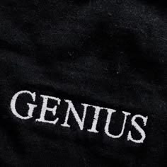 the word genius is written in white on a black shirt that has been embroidered onto it