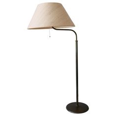 a floor lamp with a white shade on it's side and a black base