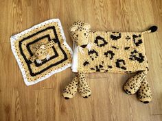 a crocheted stuffed animal next to a knitted square on the floor with it's eyes closed