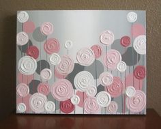 a painting with pink and grey flowers on it sitting on a table next to a wall