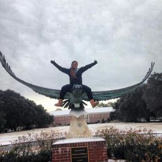 a woman is sitting on top of a statue