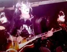 the band kiss is performing on stage with their guitars in front of them, while wearing black and white makeup