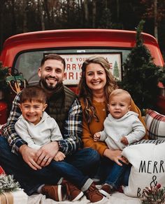 a man and woman sitting in the back of a red truck with their two children