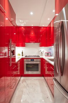 a red kitchen with stainless steel appliances and marble flooring is seen in this image