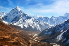 the mountains are covered in snow and brown grass, with a river running between them